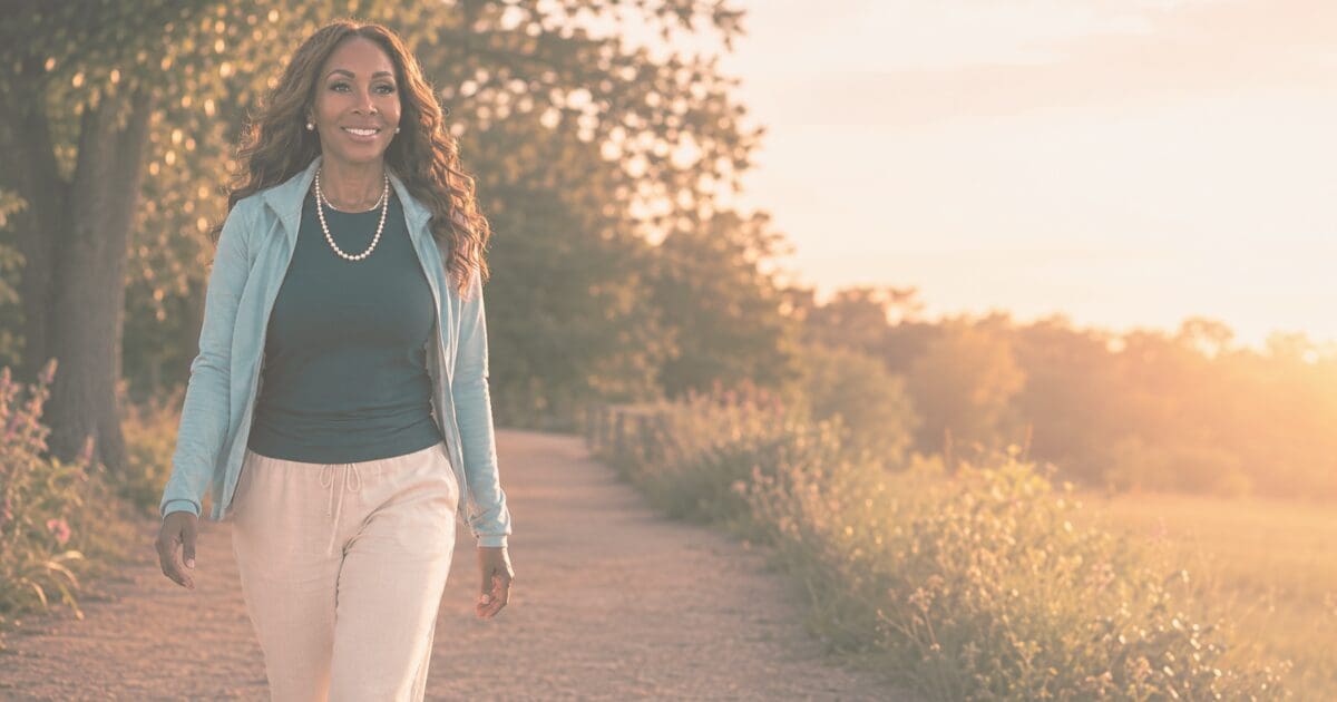 A woman walking forward on a sunlit path, for the Prayer & Perspective devotional "God Is Bigger Than Your Unanswered Questions"