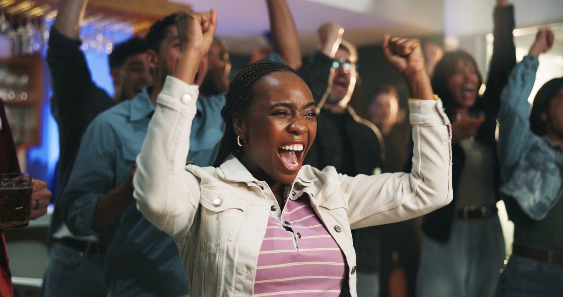 Woman celebrating with raised arms while friends cheer around her.