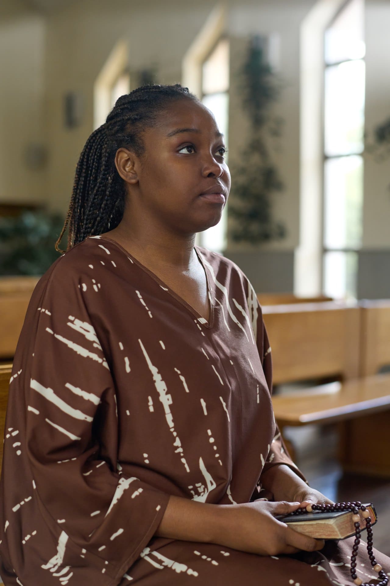 Woman seated in a church holding beads in her hands.
