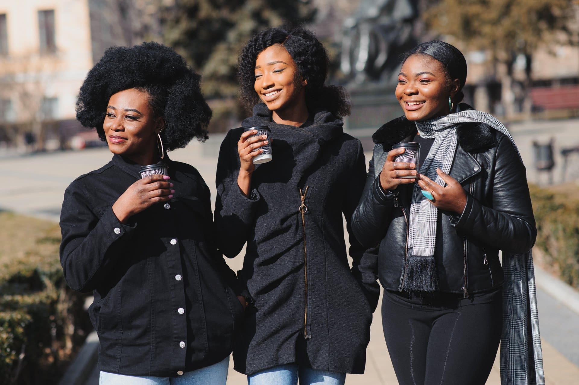 Three women walking outside with takeaway coffee cups.