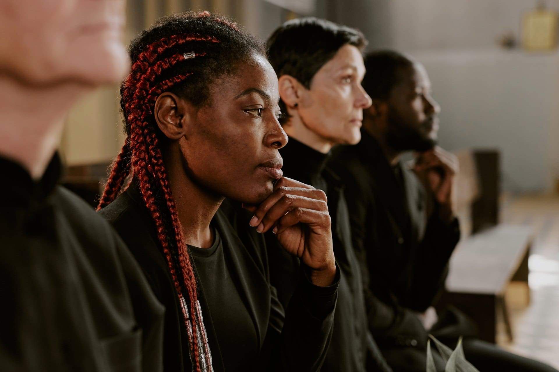 Women seated attentively in a church with one resting her chin on her hand.