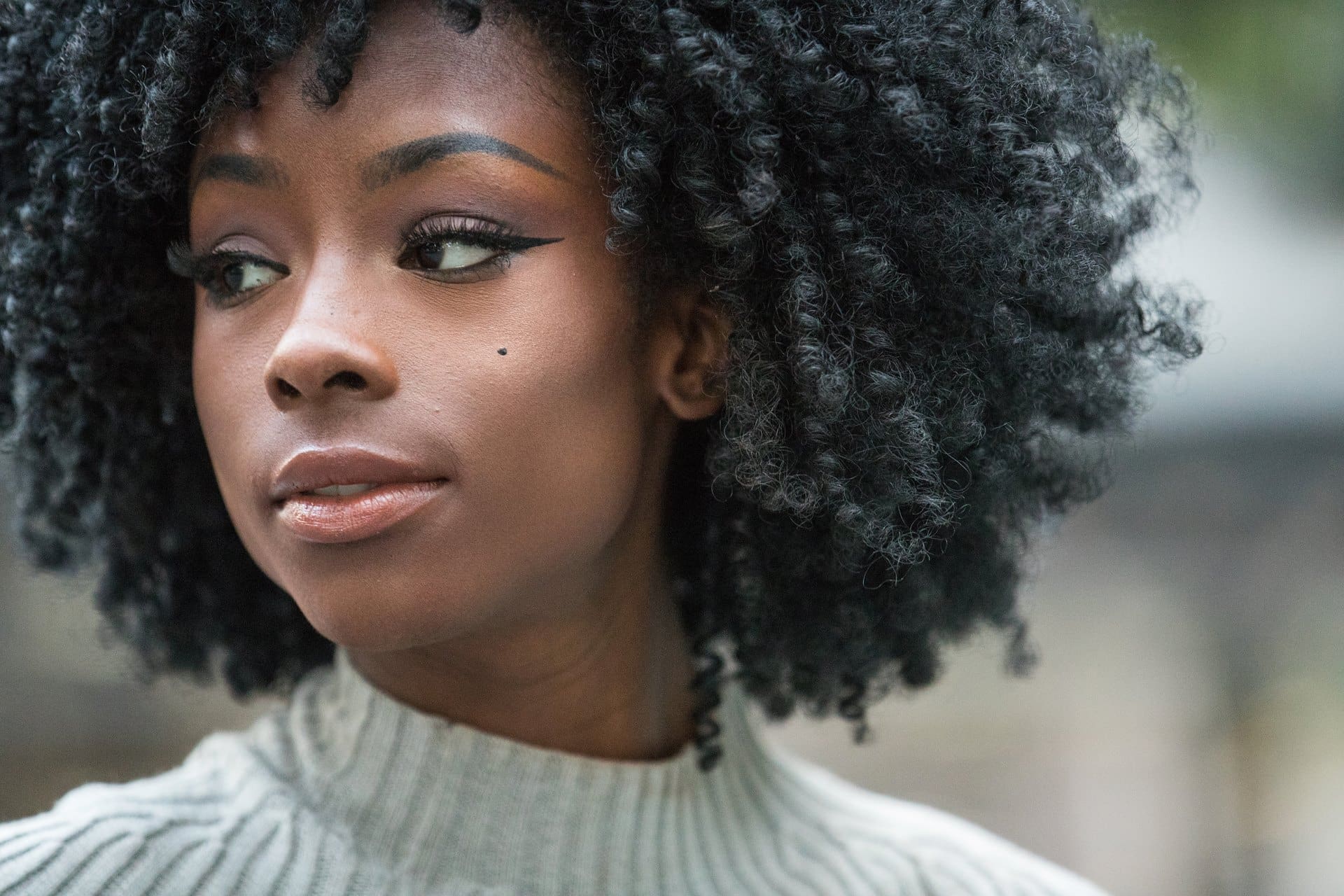 Portrait of a woman with curly hair wearing a light turtleneck sweater.