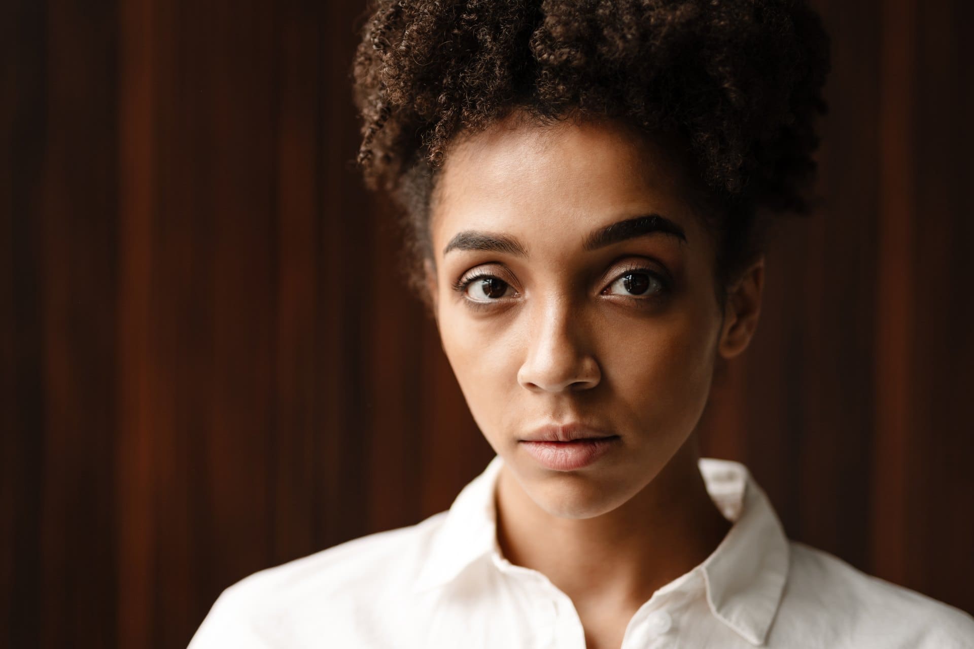 Close-up portrait of a woman with curly hair wearing a white shirt.
