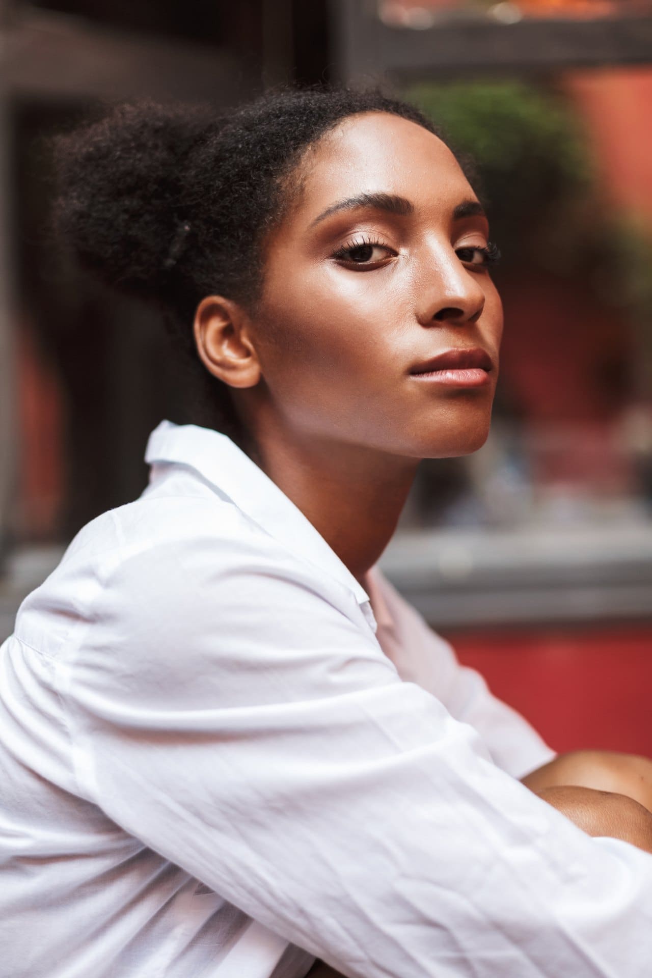 Woman in a white shirt seated outdoors looking toward the camera.