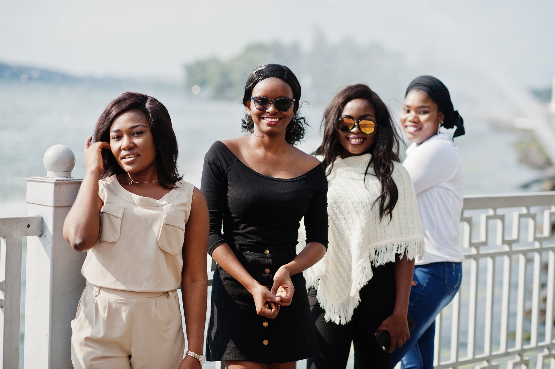 Four women standing together beside a waterfront railing.