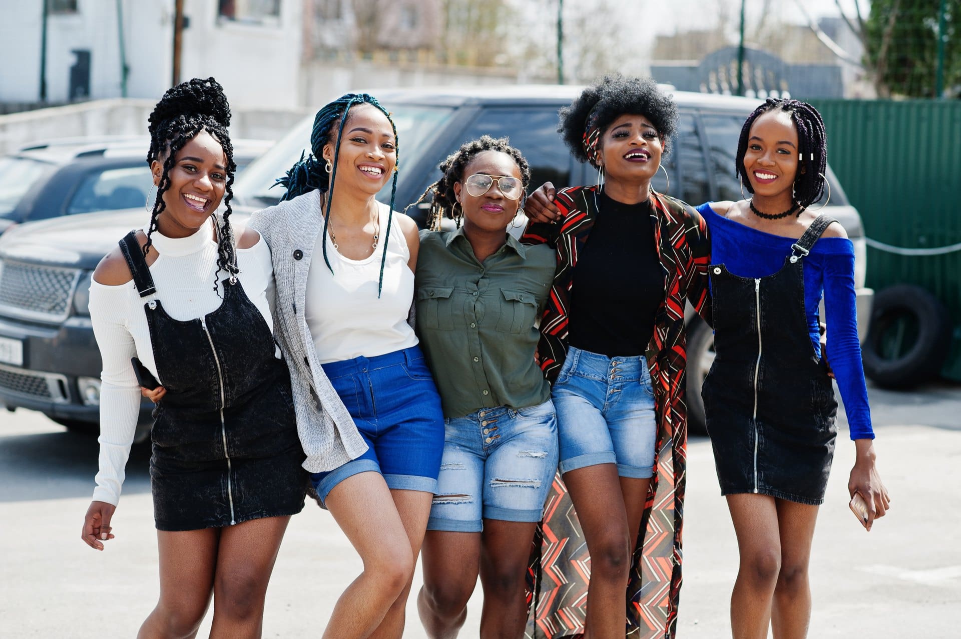 Five women walking together on a city sidewalk.