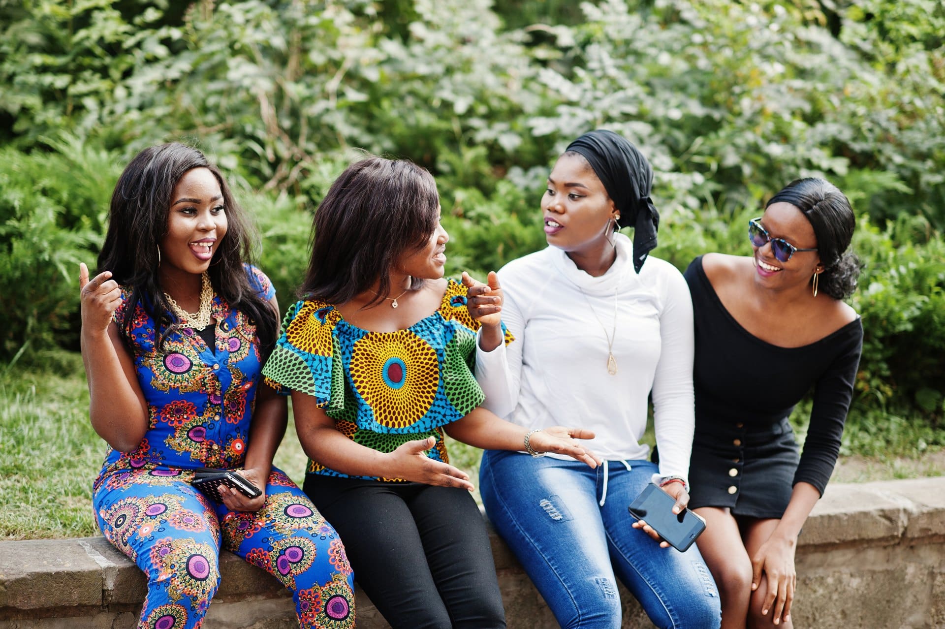 Four women sitting together on a park bench.