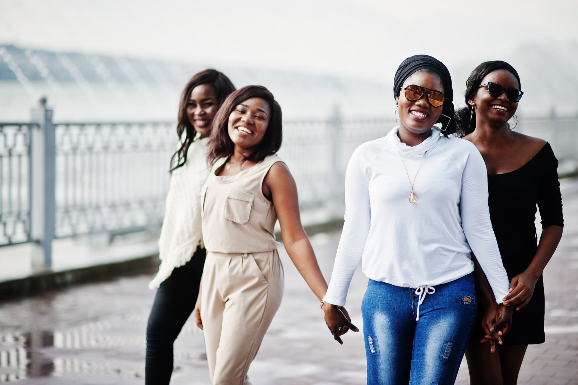 Three women walking together beside a waterfront railing.
